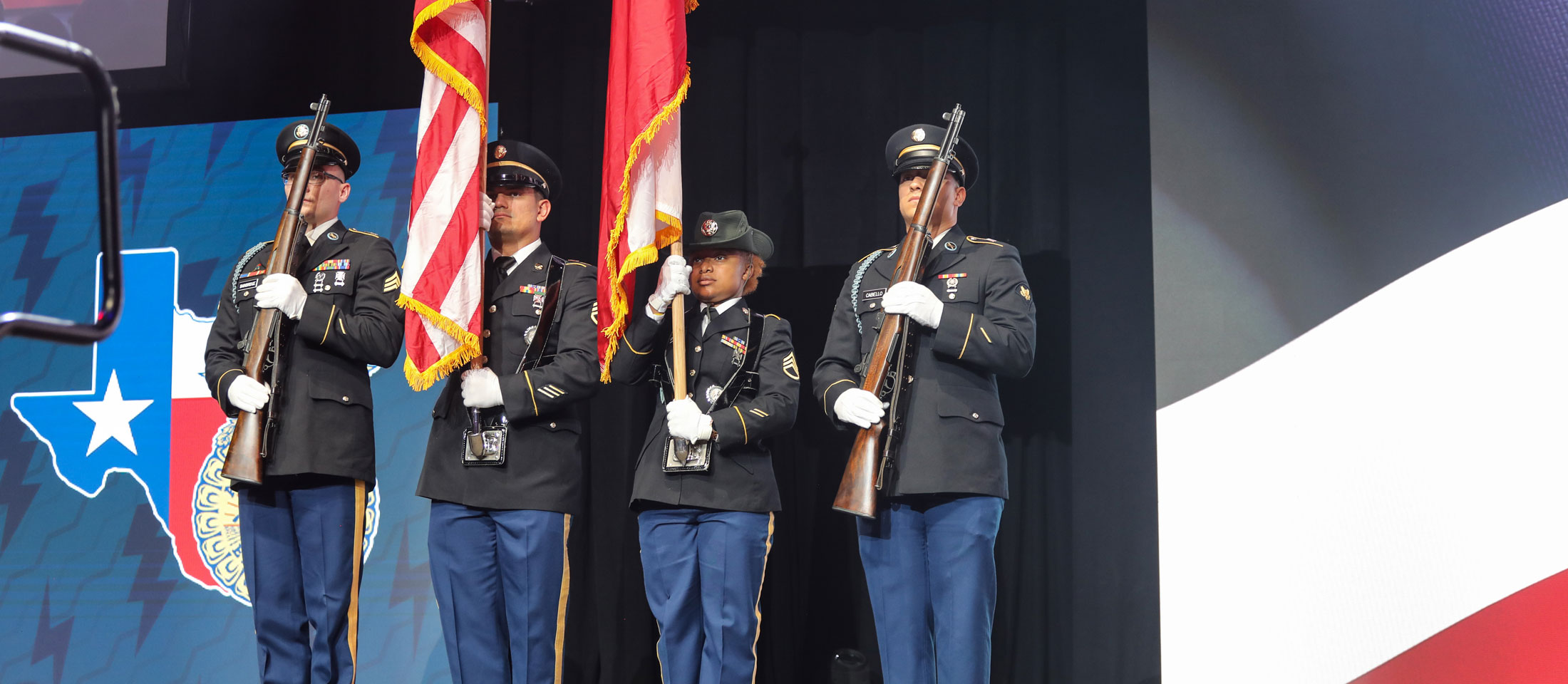 Men in uniform pose while saluting the American Flag